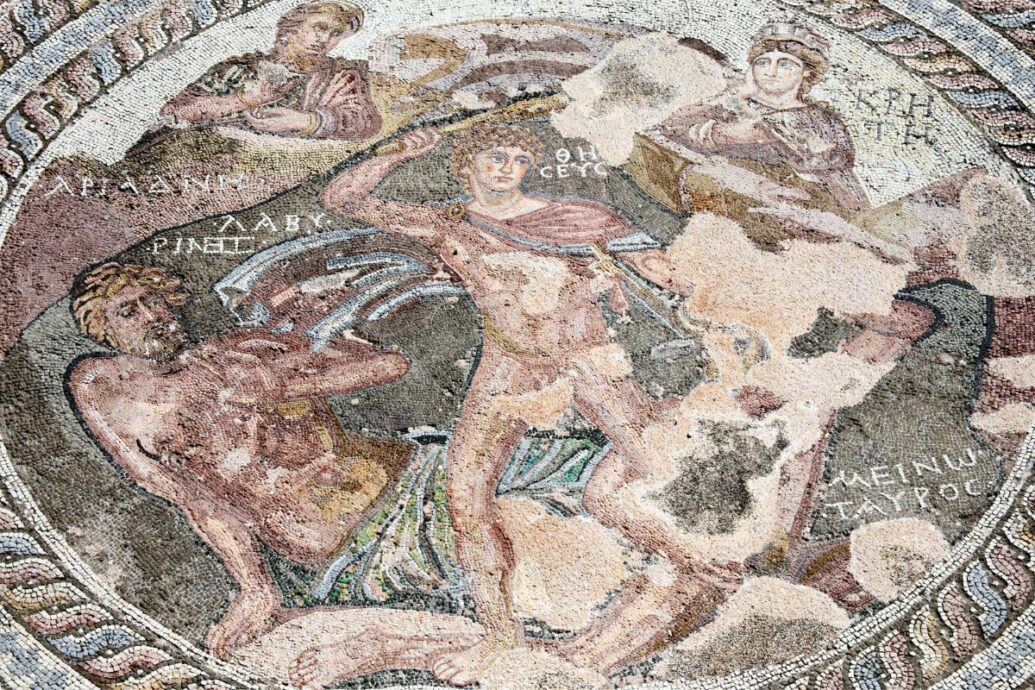 The image depicts a mosaic showing Theseus slaying the Minotaur, with other figures observing the scene.