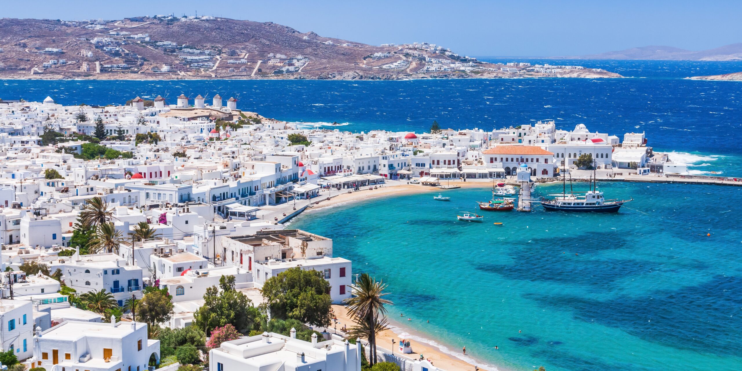A picturesque view of Mykonos, showcasing its iconic white buildings, vibrant blue sea, and charming waterfront.